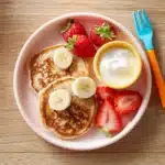 Banana oat pancakes with fruit on a toddler plate