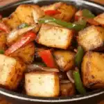 A skillet filled with crispy Potatoes O’Brien made with diced golden potatoes, bell peppers, and onions, served hot on a rustic wooden table.