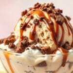 A bowl of creamy peanut butter brownie cheesecake swirl ice cream with visible chunks of brownie and swirls of cheesecake.