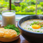 A traditional Chinese breakfast spread on a wooden table with congee, baozi, youtiao, doujiang, and jianbing, bathed in soft morning light.