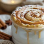 Gluten-free cinnamon roll in a white mug drizzled with sugar glaze