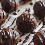 Healthy brownie protein bites arranged on parchment paper with chocolate drizzle