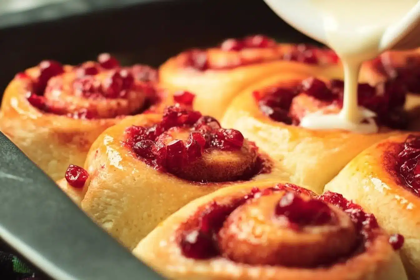 Freshly baked cranberry orange sweet rolls on a cooling rack.