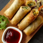 Plate of crispy veggie spring rolls with dipping sauce