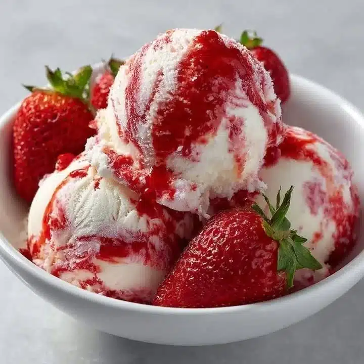 Delicious strawberry swirl ice cream in a bowl with fresh strawberries