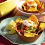 Delicious Mexican nachos baskets topped with cheese, jalapeños, and guacamole.