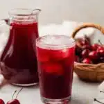 Glass of cherry pie iced tea with fresh cherries and pie crust garnish