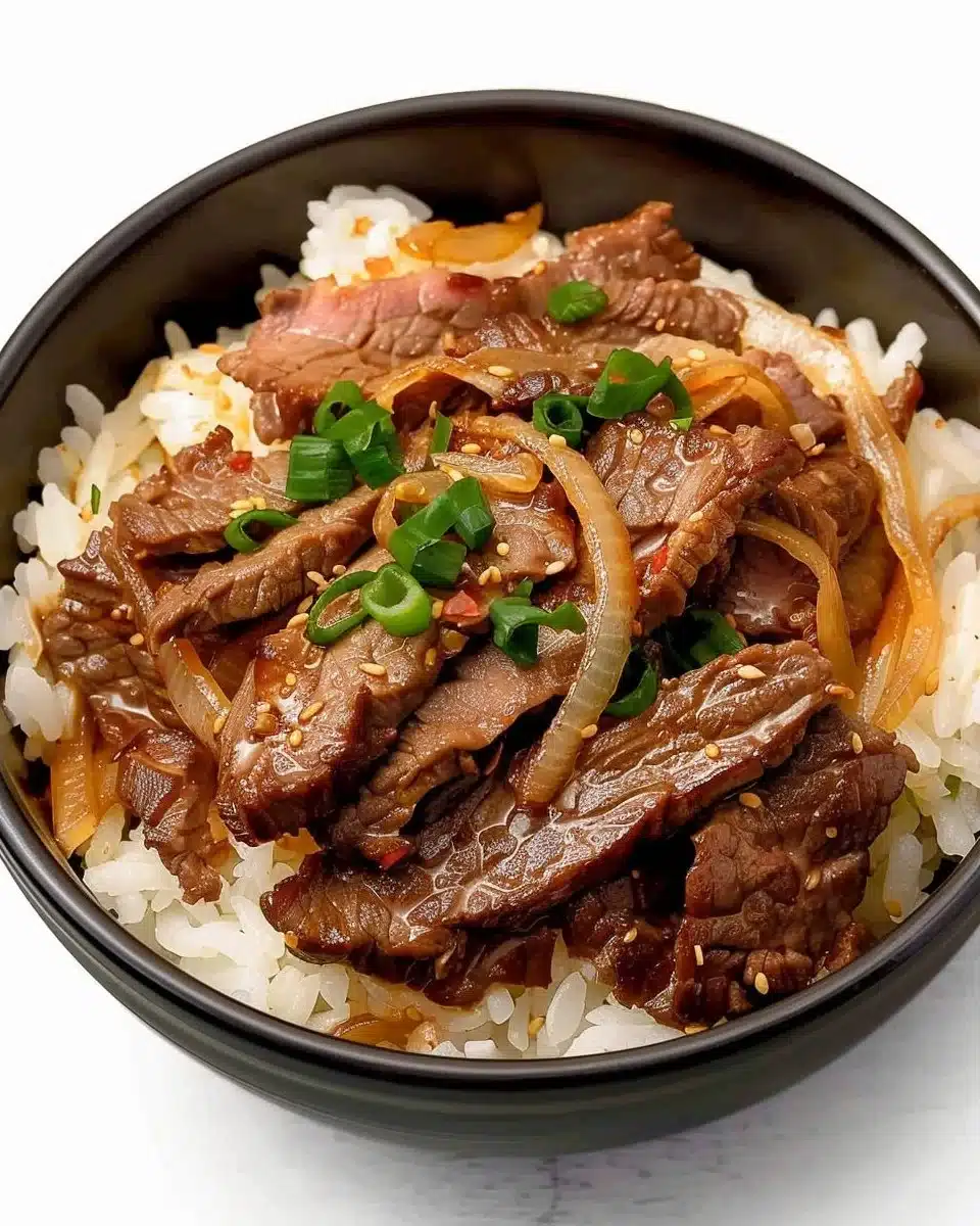 Delicious homemade copycat Yoshinoya Beef Bowls topped with onions and sauce.
