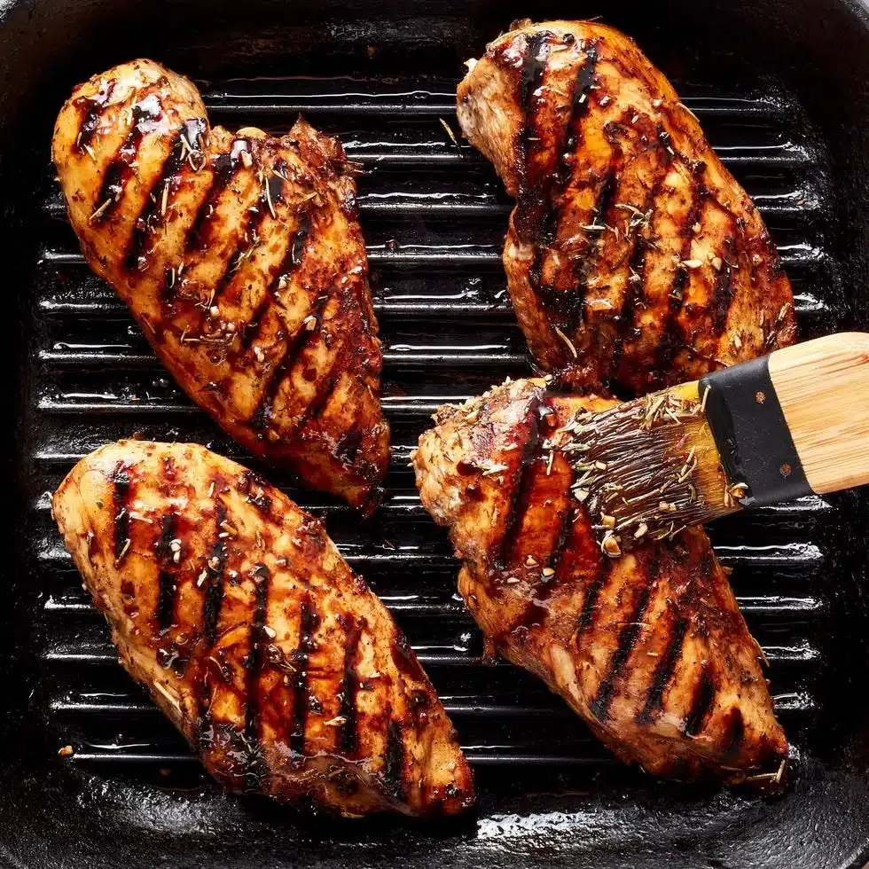 Delicious grilled chicken breast on a plate garnished with herbs.