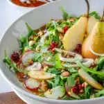 Fresh pear salad with greens, nuts, and cheese on a plate