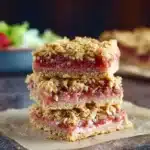 Delicious homemade rhubarb crumble bars on a rustic wooden table.