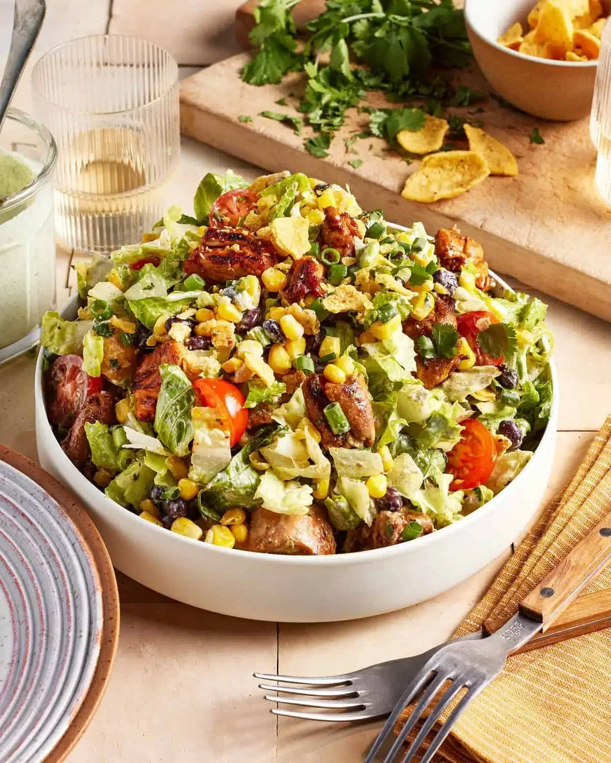 A vibrant bowl of BBQ chicken salad topped with fresh vegetables and a smoky sauce.