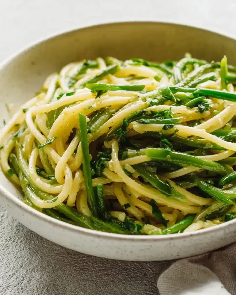 Garlic scape pasta garnished with fresh herbs and cheese