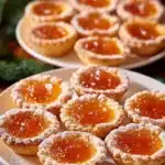 Homemade simple mini apricot tarts with fresh apricots on a wooden table.