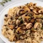 Creamy Mushroom Risotto Parmesan topped with fresh herbs and cheese in a bowl.