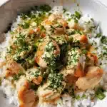 Creamy garlic chicken rice bowls topped with fresh herbs and served in a bowl.