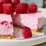 No Bake Raspberry Cheesecake topped with fresh raspberries on a white plate.