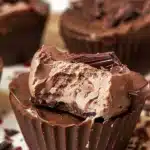 Nutella cheesecake chocolate cups topped with chocolate drizzle and hazelnuts